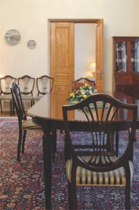 Saikingai dekoruotame valgomajame – elegantiški tamsaus medžio baldai, o kambaryje privaloma puošmena – spalvingas turkiškas kilimas.