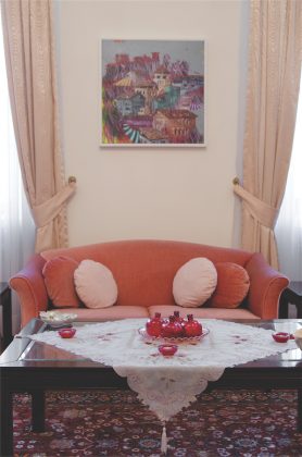 Mažesniajame svečių priėmimo kambaryje rausva sofutė nuteikia maloniems pokalbiams. Savo koloritu dera žurnalinio staliuko puošmenos: raudono stiklo žvakidės bei granatų formos stiklo vazelės. 