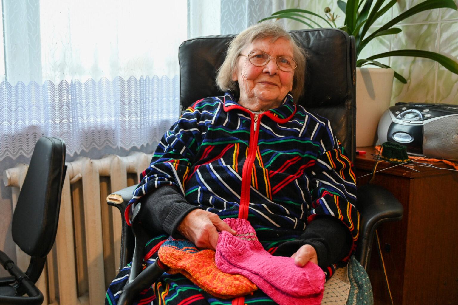 Į dešimtą dešimtį įkopusi Romualda Lukoševičienė, kuri, pasak sūnaus, ne tik nebepaeina, bet ir šaukštą rankoj sunkokai nulaiko, nuo pavasario Ukrainos kariams jau numezgė šimtą porų kojinių – po vieną per dieną.