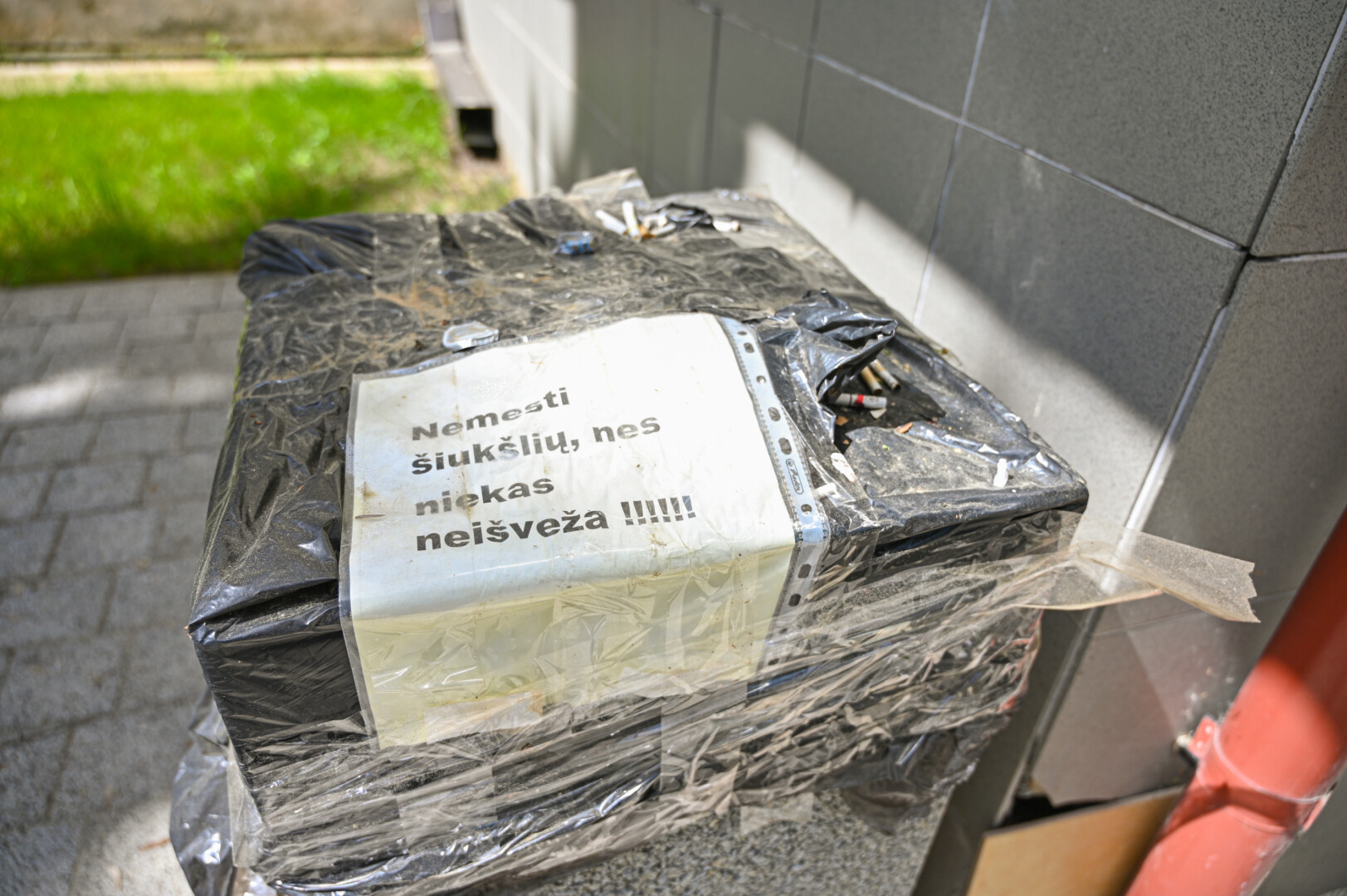 Gyventojai, nebeapsikentę iš šiukšliadėžių virstančių atliekų, kurias išnešioja vėjas ir paukščiai, pradėjo klijuoti prašymus nebemesti šiukšlių. P. ŽIDONIO nuotr.